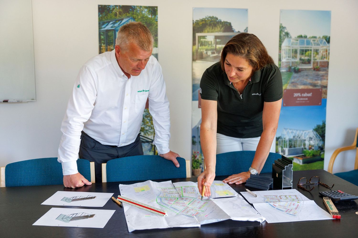 Two people reviewing architectural plans and documents on a table.