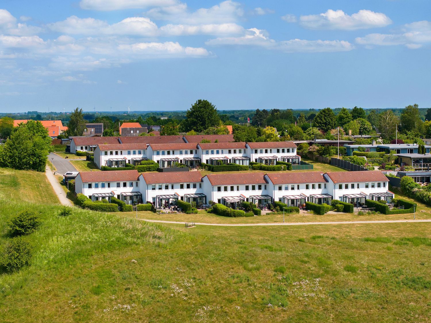 Aerial view of curved row of white townhouses in suburban development.