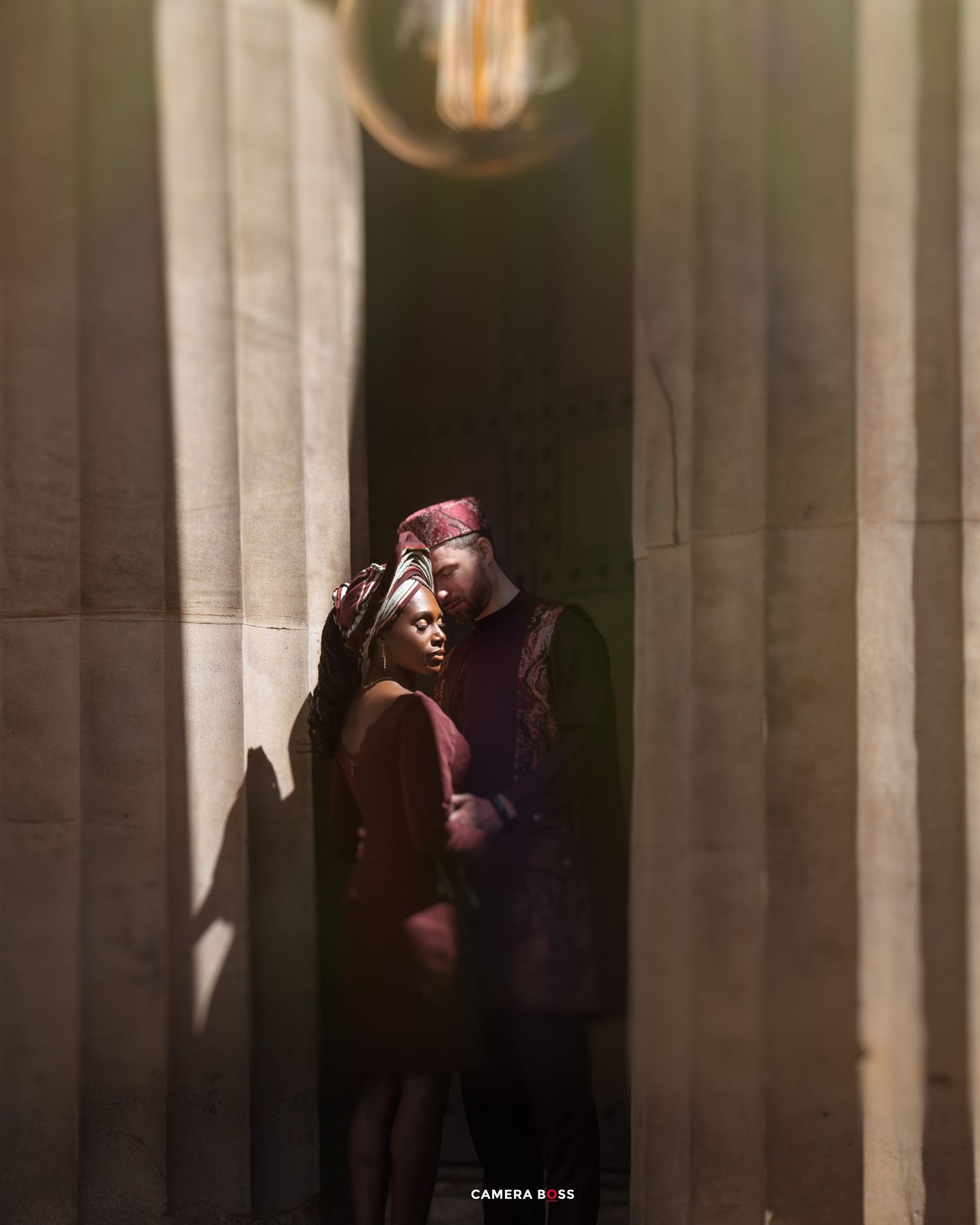 A silhouetted couple embraces among illuminated white columns creating a romantic architectural composition.