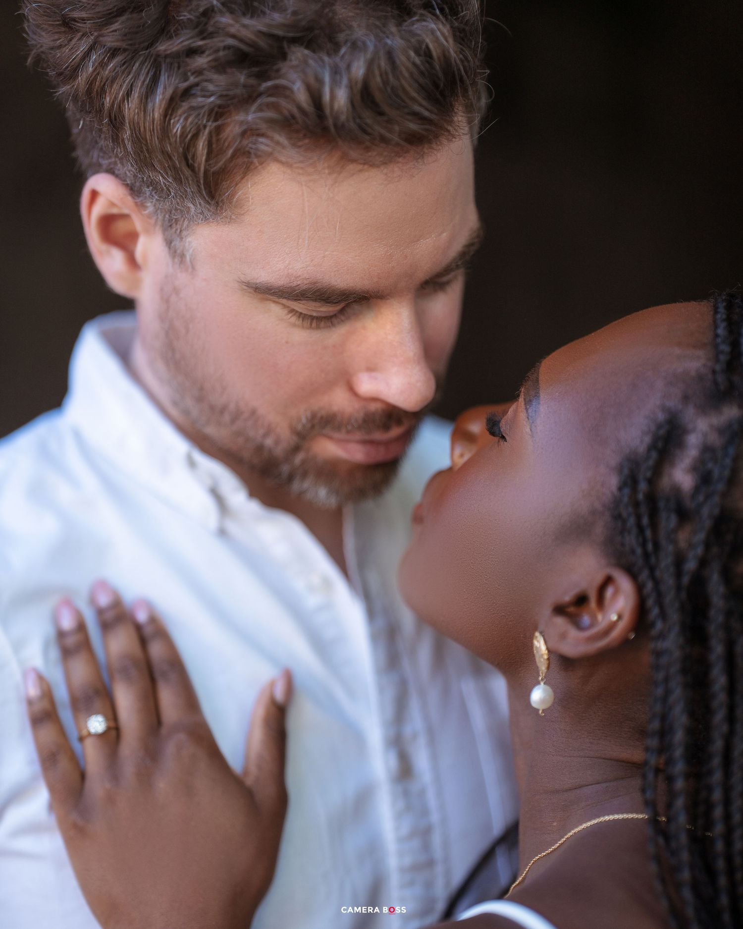 A couple shares an intimate embrace while smiling and touching foreheads in what appears to be an engagement photo sequence.
