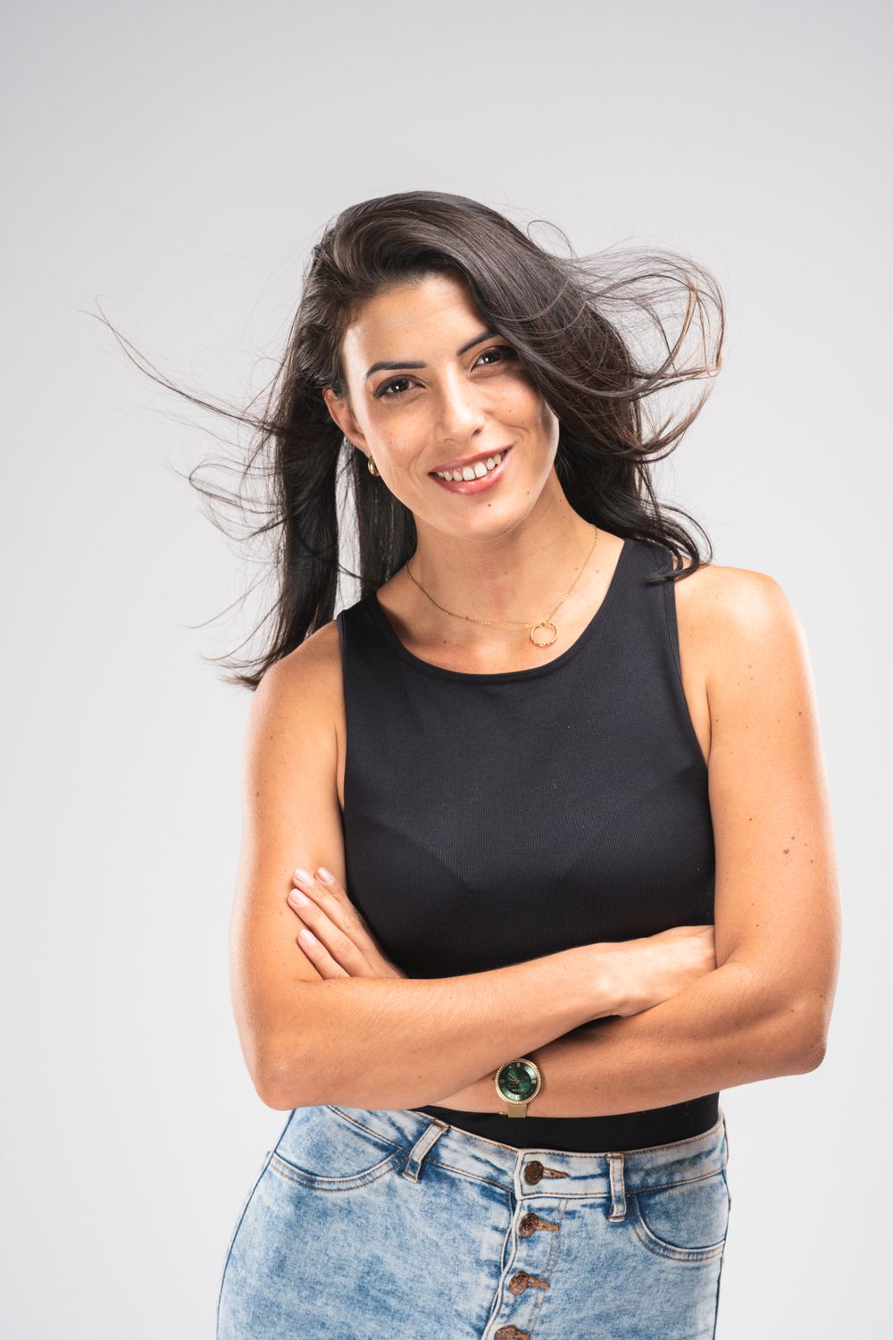 Stylish portrait of someone in black crop top and denim with windswept dark hair.