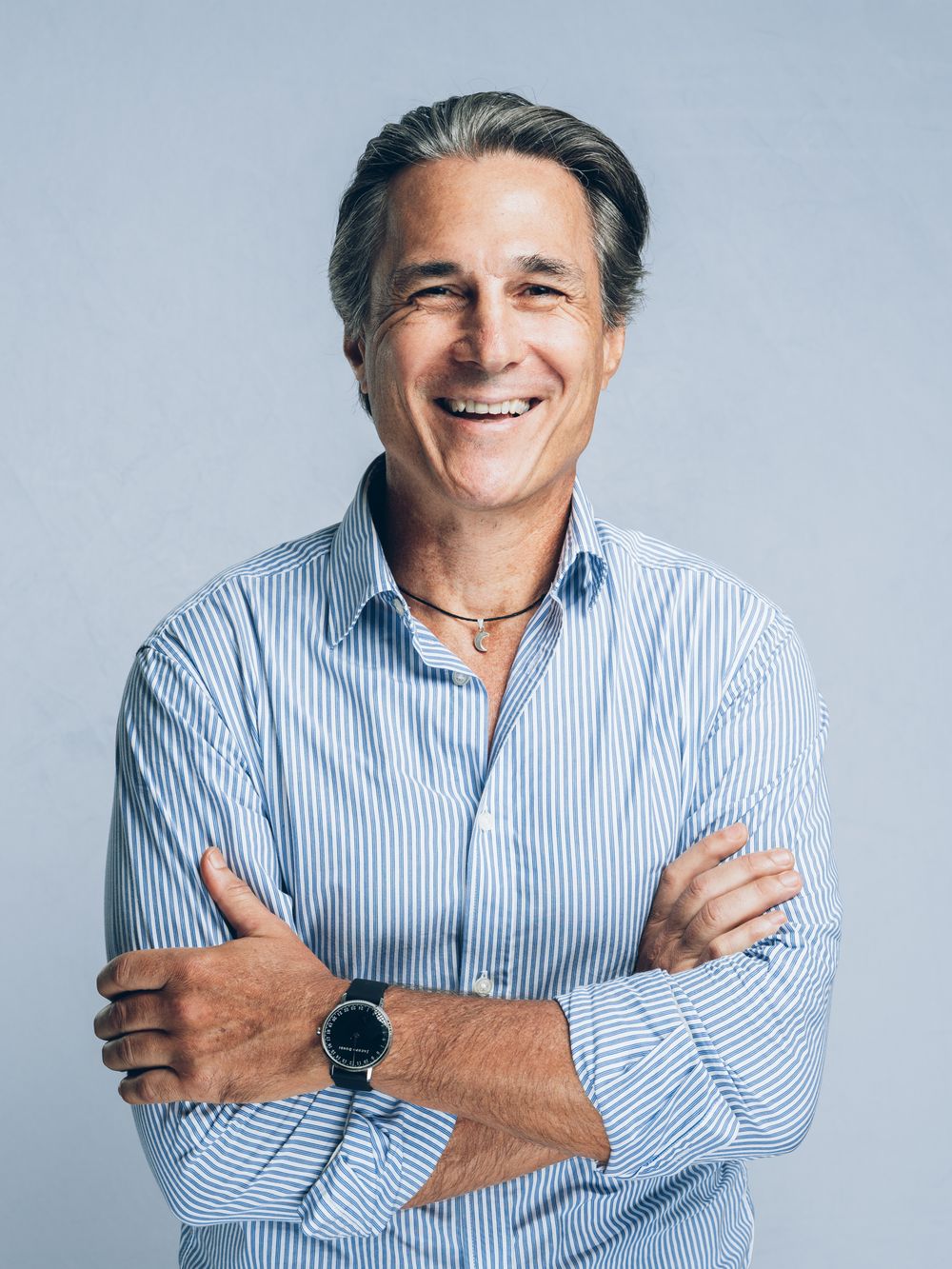 A middle-aged man wearing blue striped shirt is shown laughing and smiling in a photo series against a gray background.