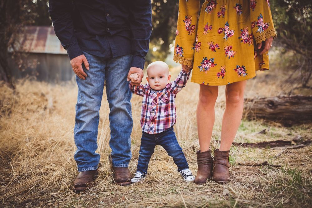 A close-up view of family members' shoes and feet standing together on outdoor terrain.