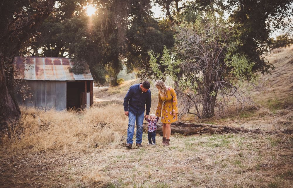 A group walks along a hillside path through dry golden grass during sunset.