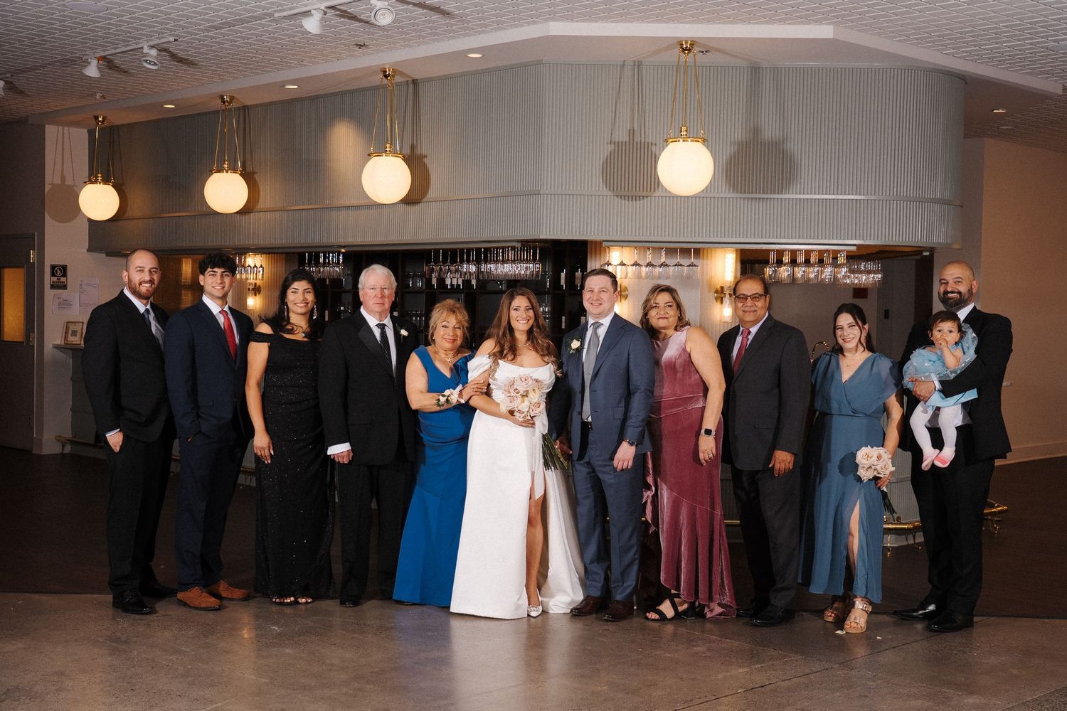 A group poses together at a formal event with elegant lighting and decor in an indoor venue.
