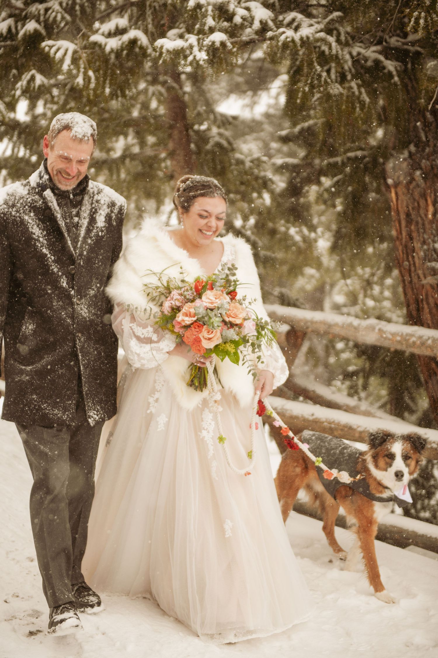 Couple stands in snowy winter forest celebrating their wedding day as melting snow falls around them.