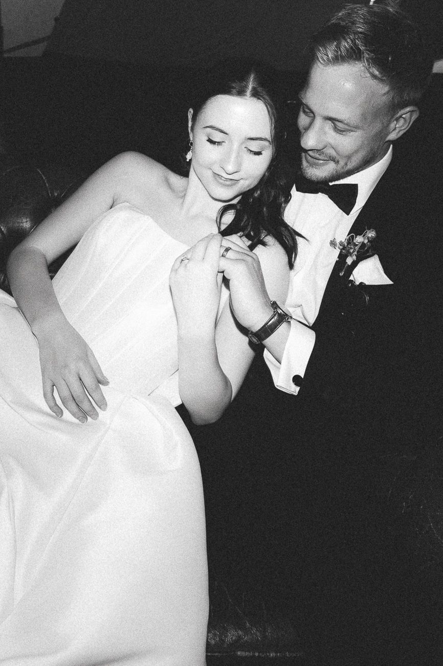 A romantic black and white wedding photo showing a couple sharing an intimate dance moment in formal attire.
