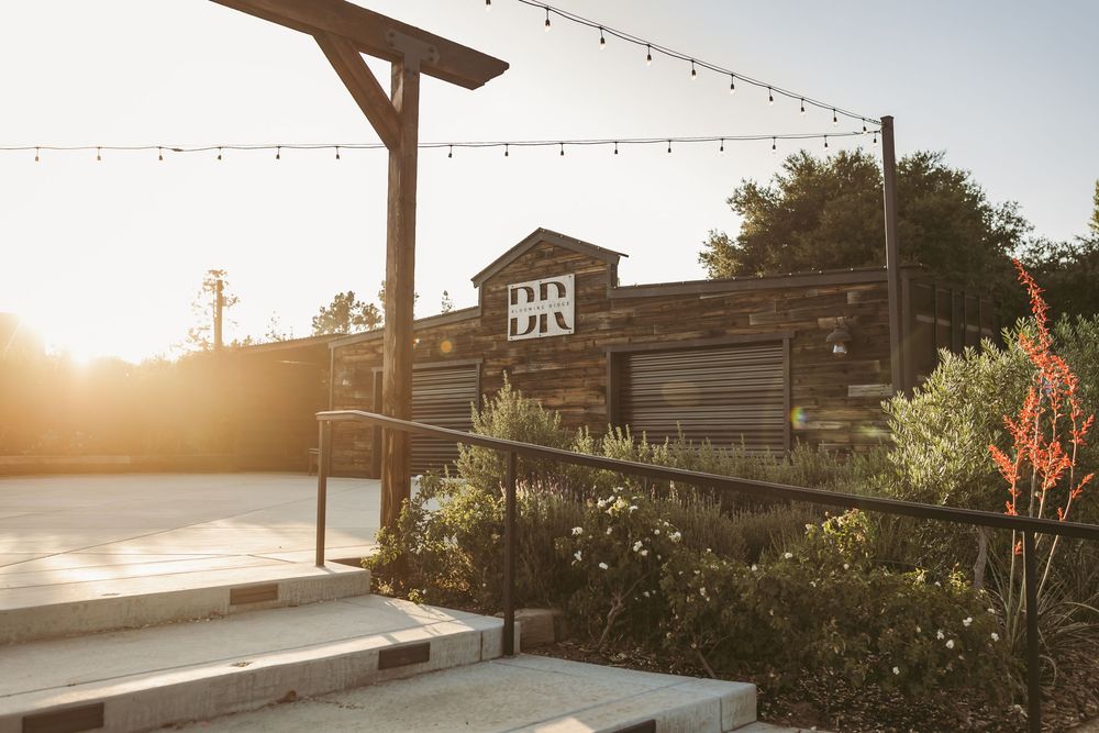 Rustic wooden building with string lights and signage at golden hour.