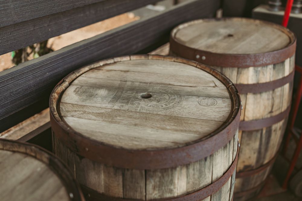 Weathered wooden whiskey barrels with rustic metal bands stacked in a row.
