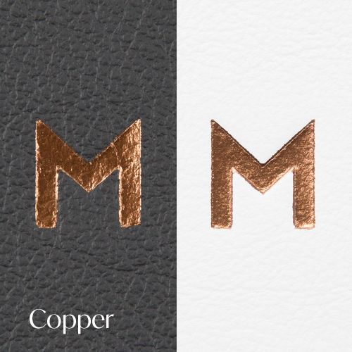 Letter M in copper foil finish shown on dark leather and white backgrounds.