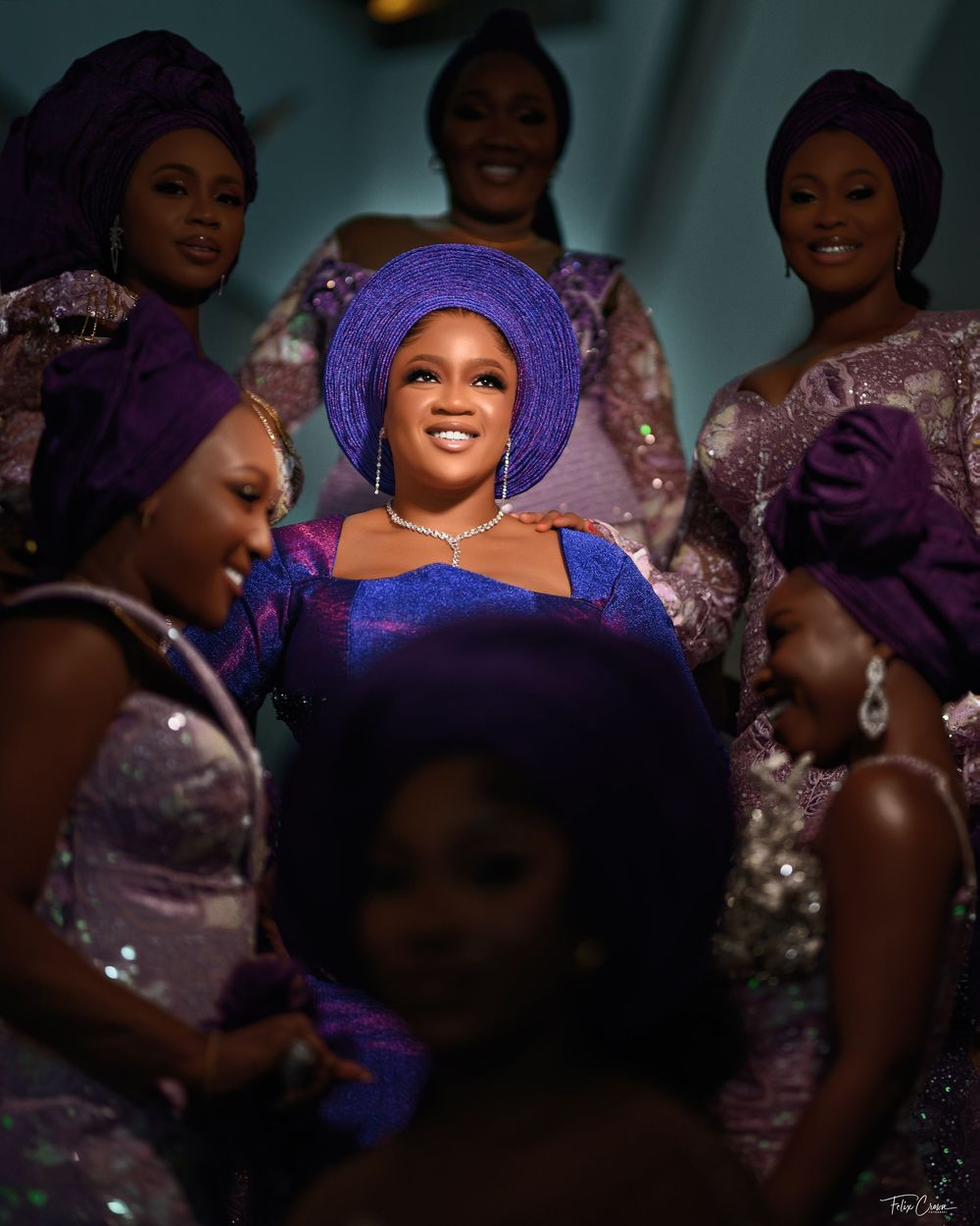 People gathered in purple and sparkly formal attire celebrate at an elegant evening event.