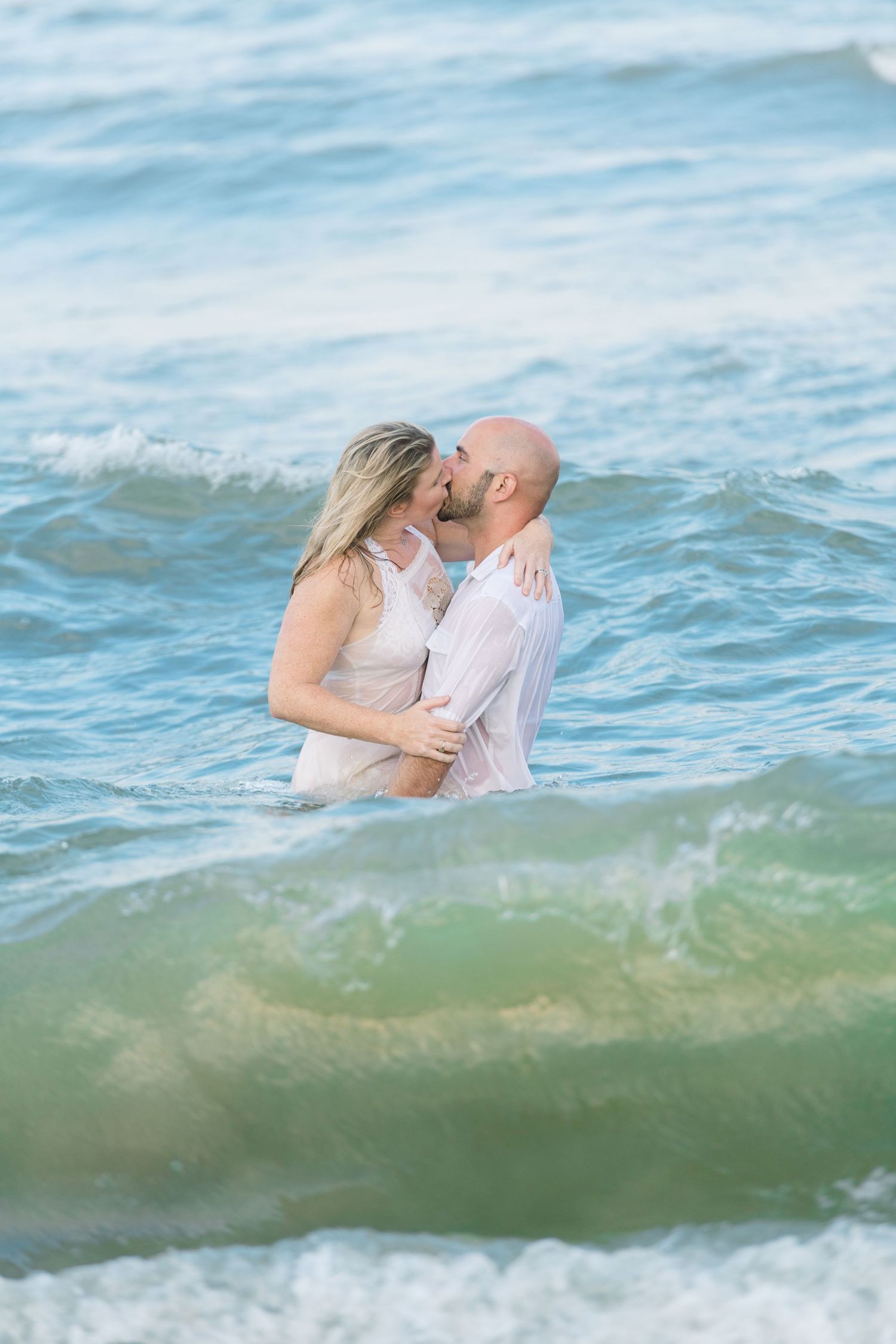Couple kissing while in the ocean along Virginia Beach. Virginia Beach Photographer.