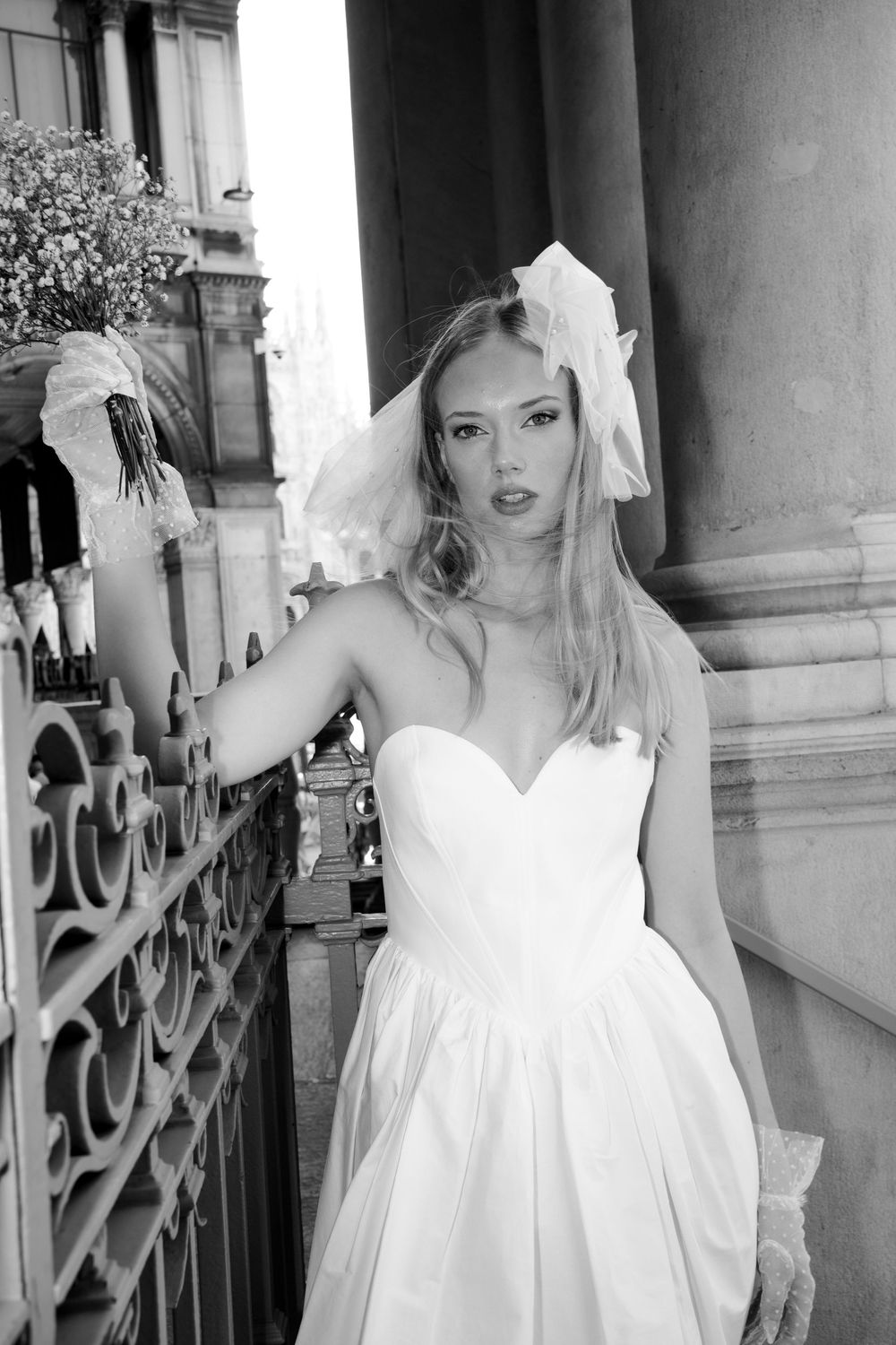 Black and white artistic photo series featuring a model in an elegant white dress posing against classic architecture.