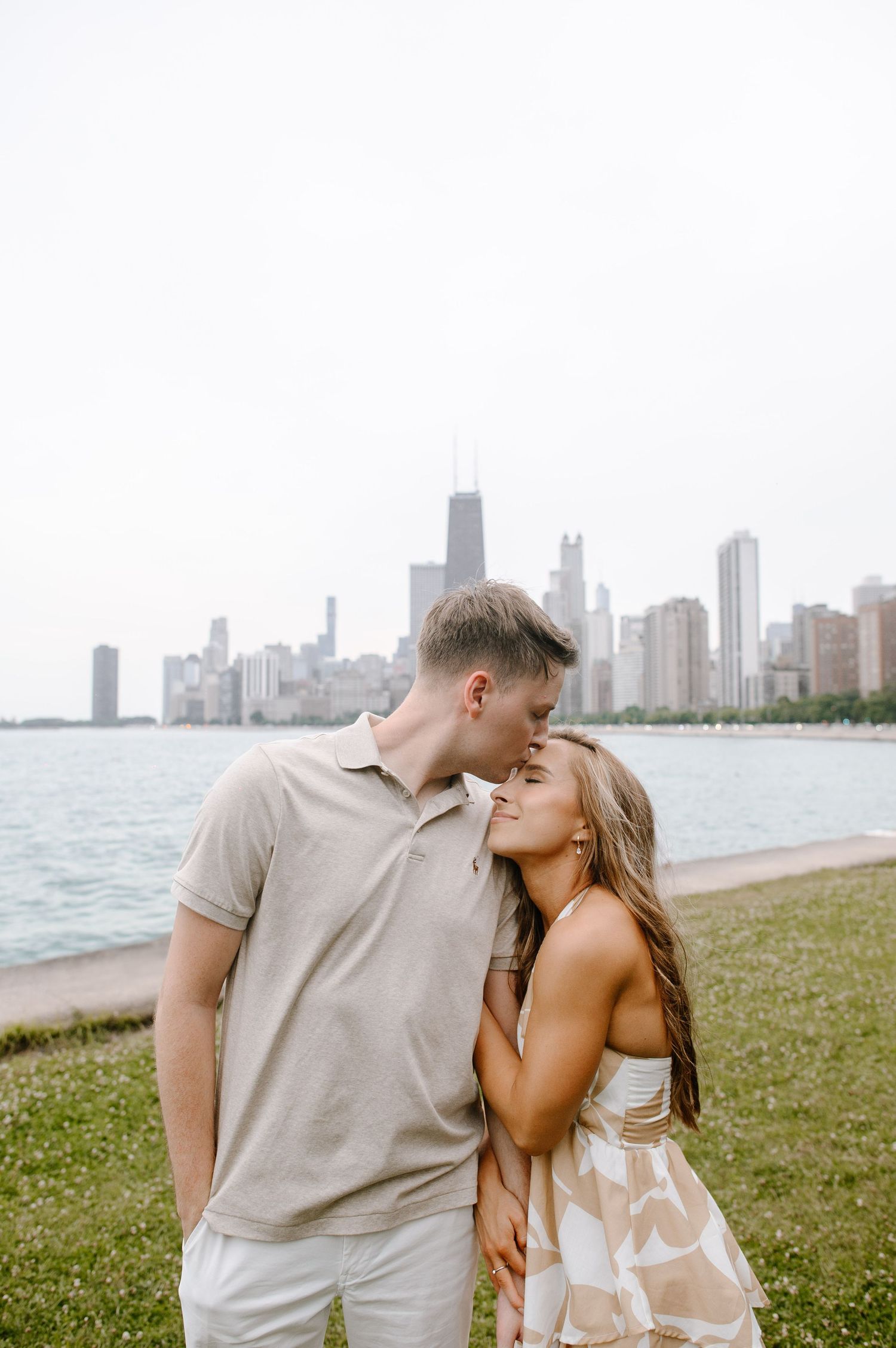 A romantic couple shares tender moments along Chicago's lakefront with the iconic skyline visible in the background.