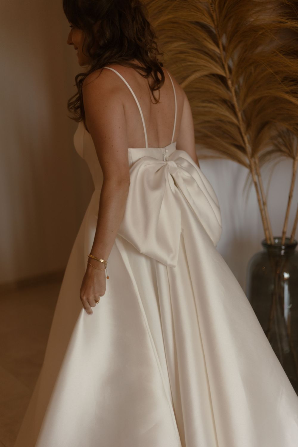 Close-up details of a flowing white satin dress with delicate spaghetti straps.