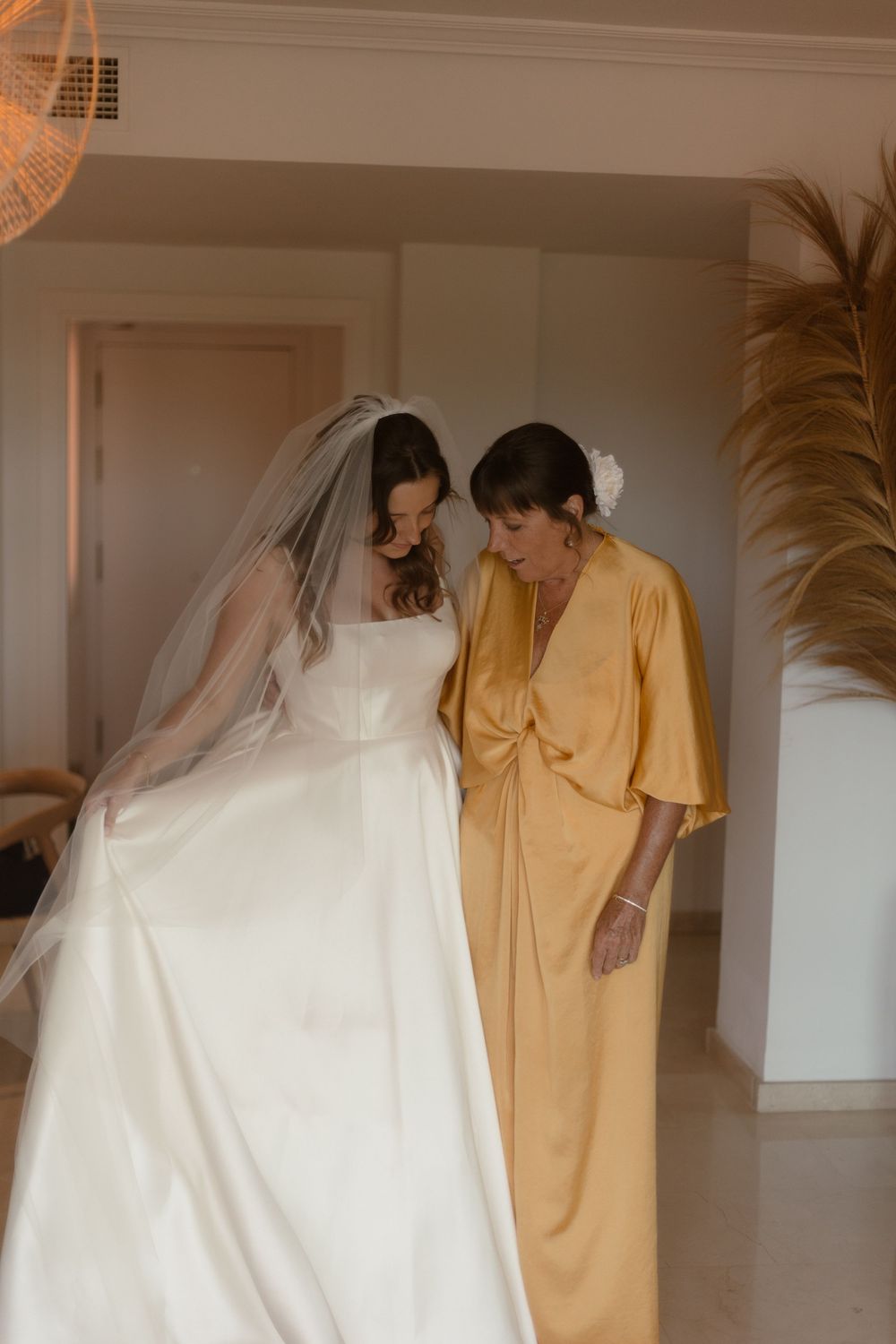 Two people in formal attire share an intimate moment, with one wearing a flowing white wedding gown and veil.