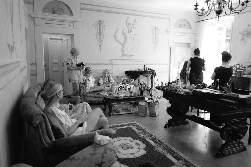 Vintage black and white photo of people relaxing in an ornate room with chandeliers and classical decor.