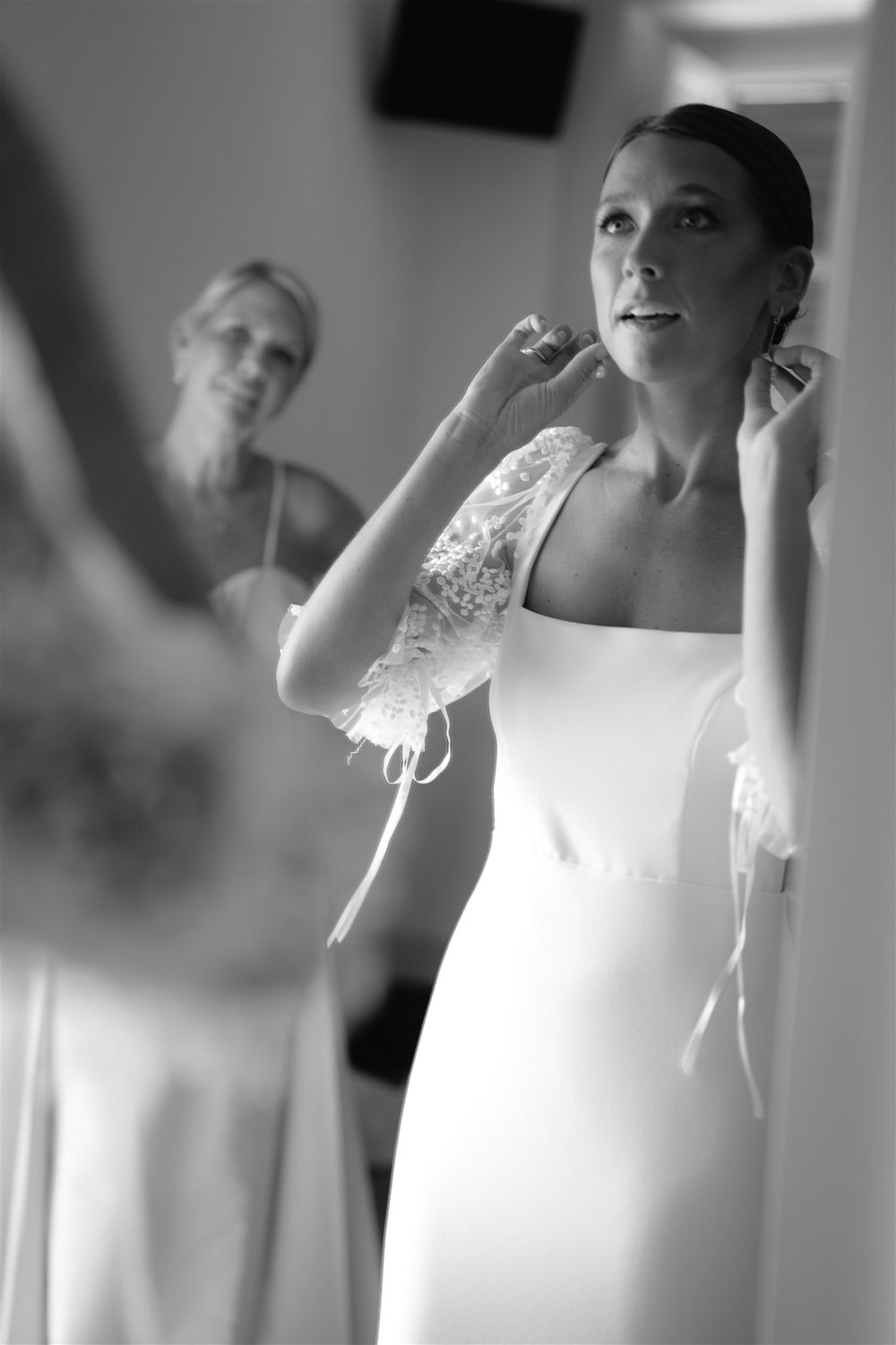 Black and white photo showing final touches of wedding day preparation in an elegant room.