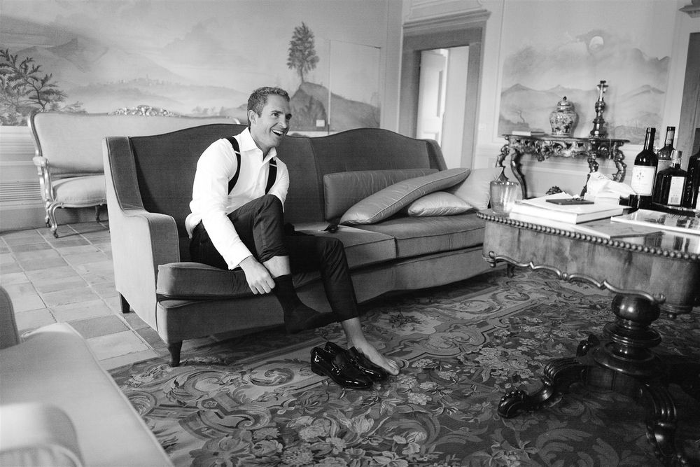 Black and white photo of someone sitting alone on an antique sofa in formal attire.
