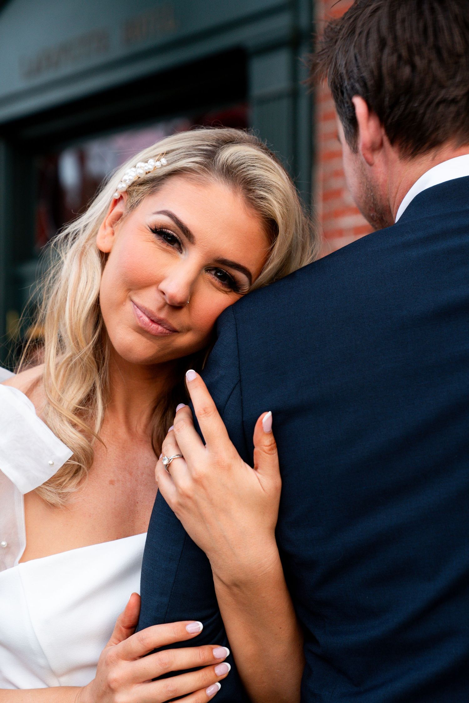 Jessica Paige Photo Co. Best Wedding Photographer. Close up of a couple sharing an intimate moment against a red brick wall exterior.