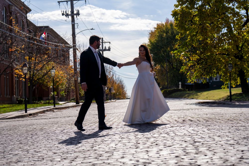 A joyful dance on cobblestone streets in wedding attire.