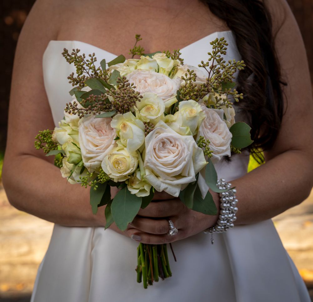 An elegant bridal bouquet of white and blush roses with delicate greenery.