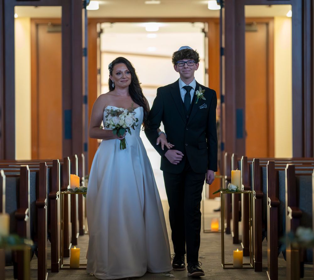 A wedding ceremony scene in a church aisle lit by candlelight.