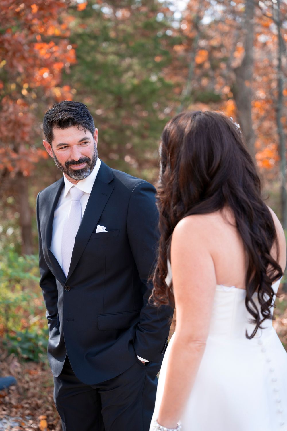 Outdoor fall wedding portrait with vibrant autumn colors in background.