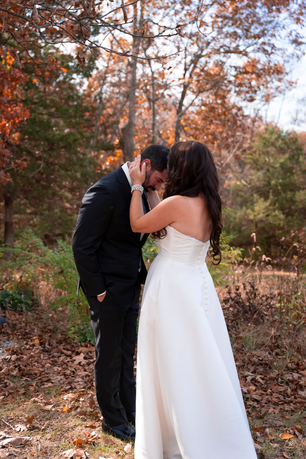 Intimate wedding moment captured in autumn forest setting.