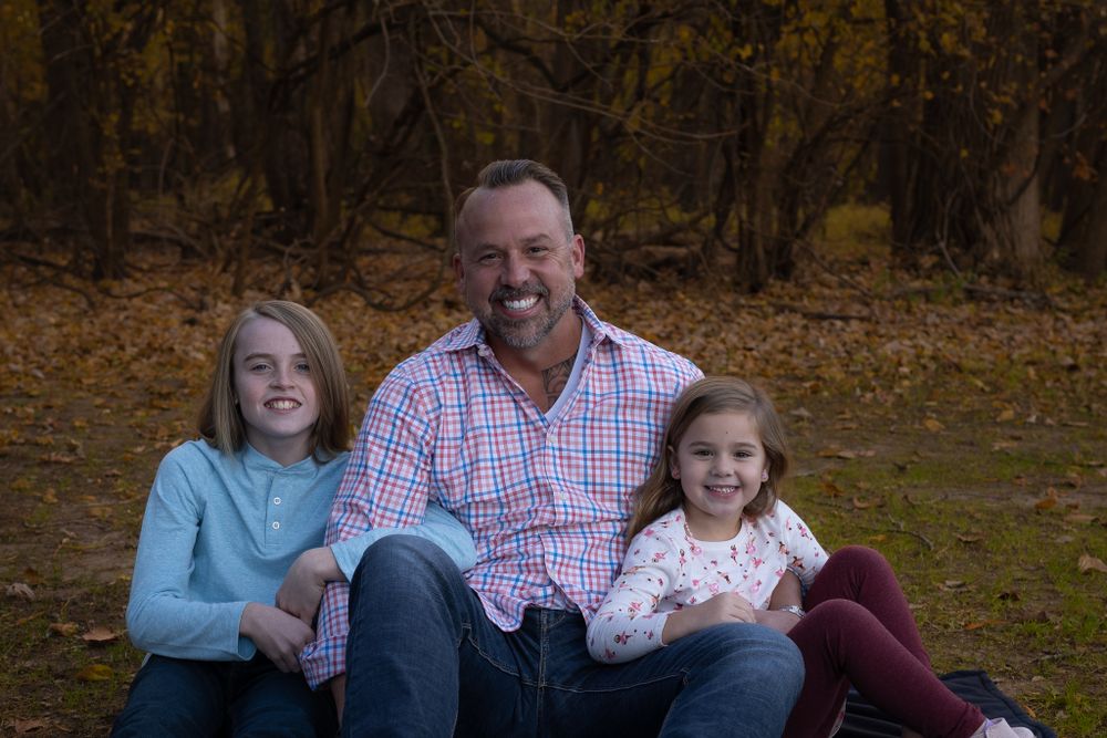 A family sits together outdoors for a portrait during autumn.