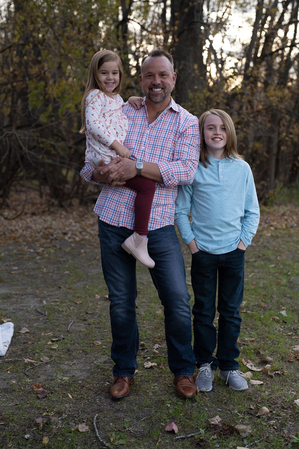 Casual outdoor family portrait with children and adult in autumn setting.