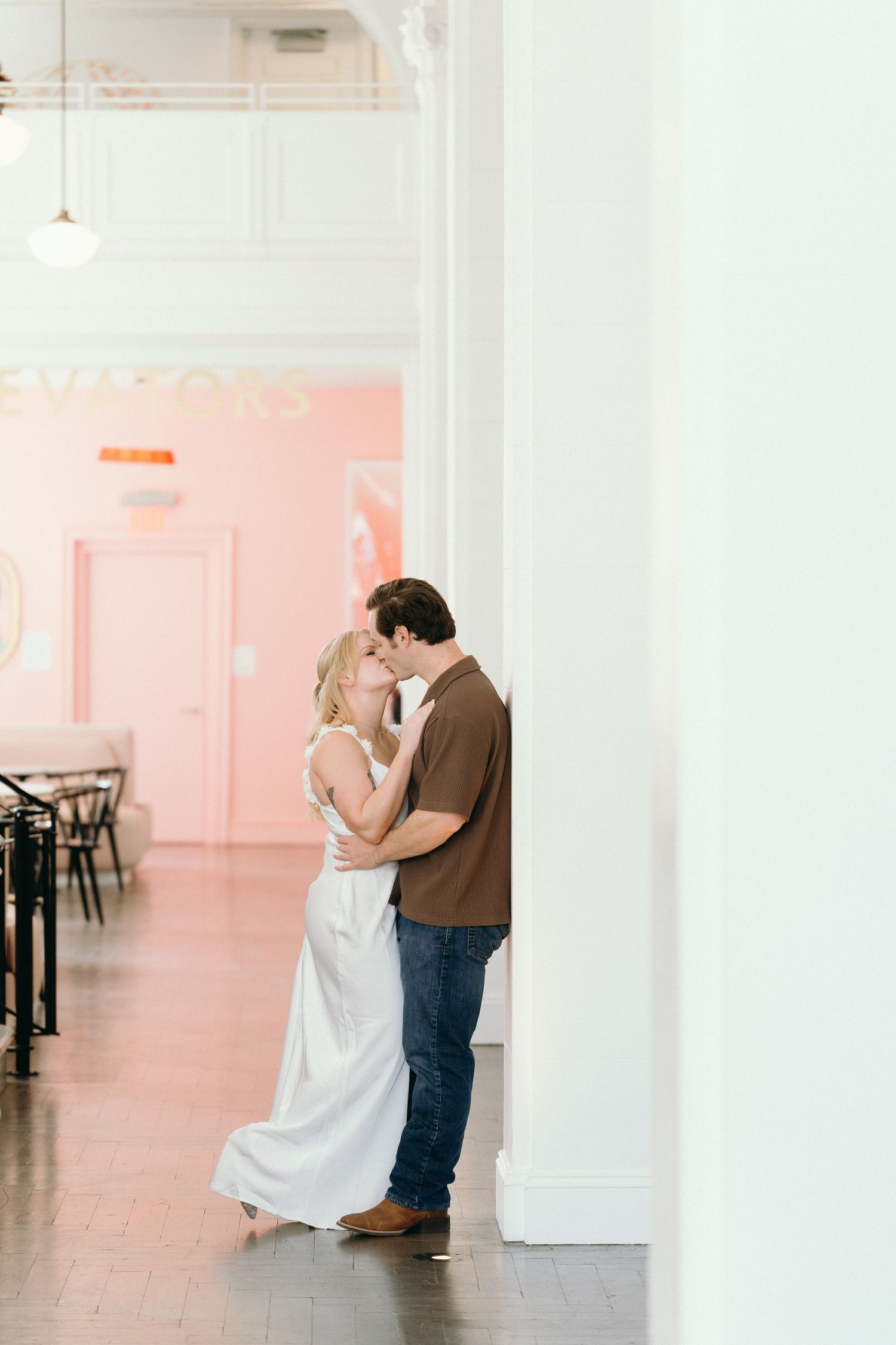 A romantic moment shared in a bright minimalist room with pink walls.