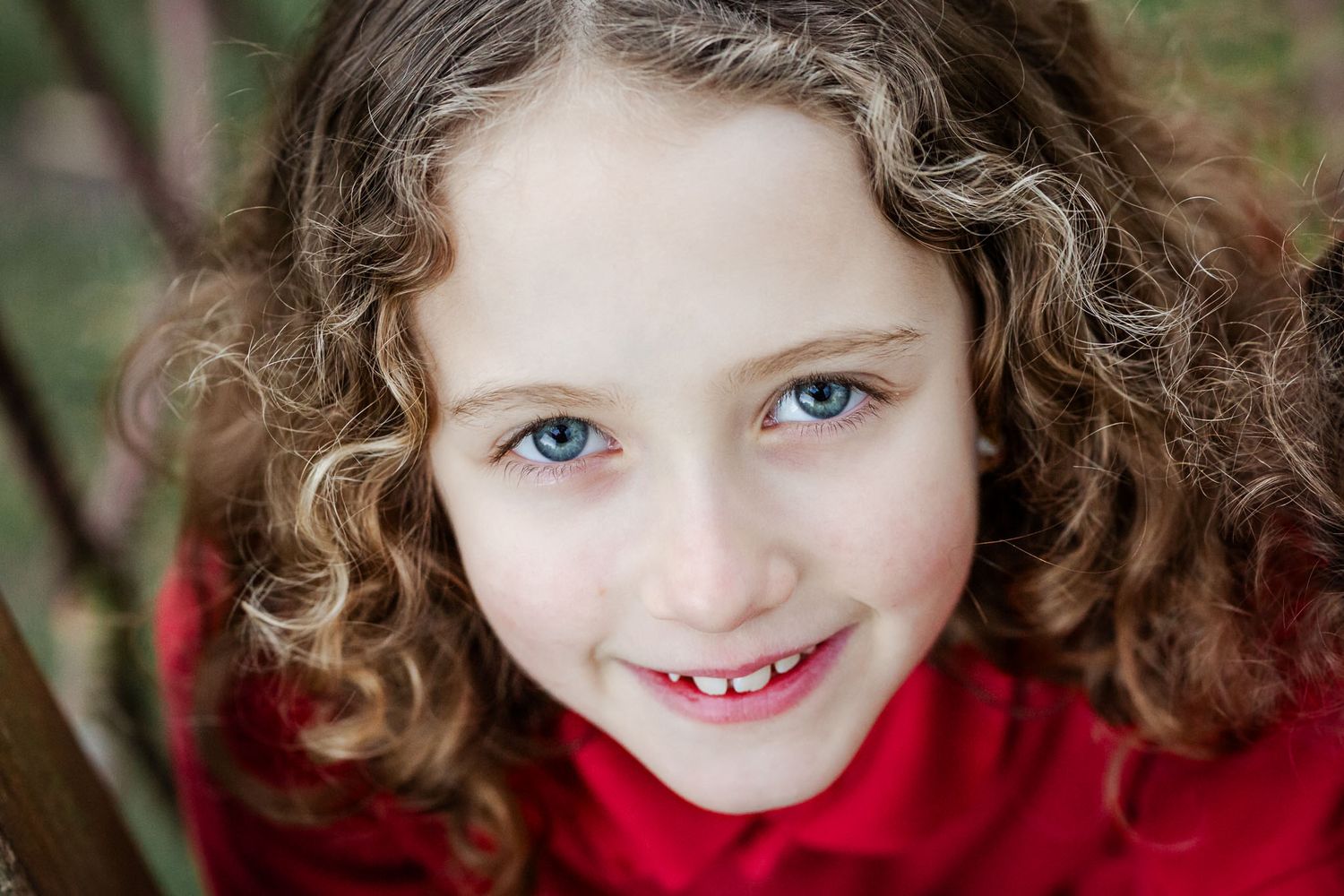 A primary school girl looks up into the camera and smiles. She looks natural and relaxed during her school photoshoot. Bristol school photos