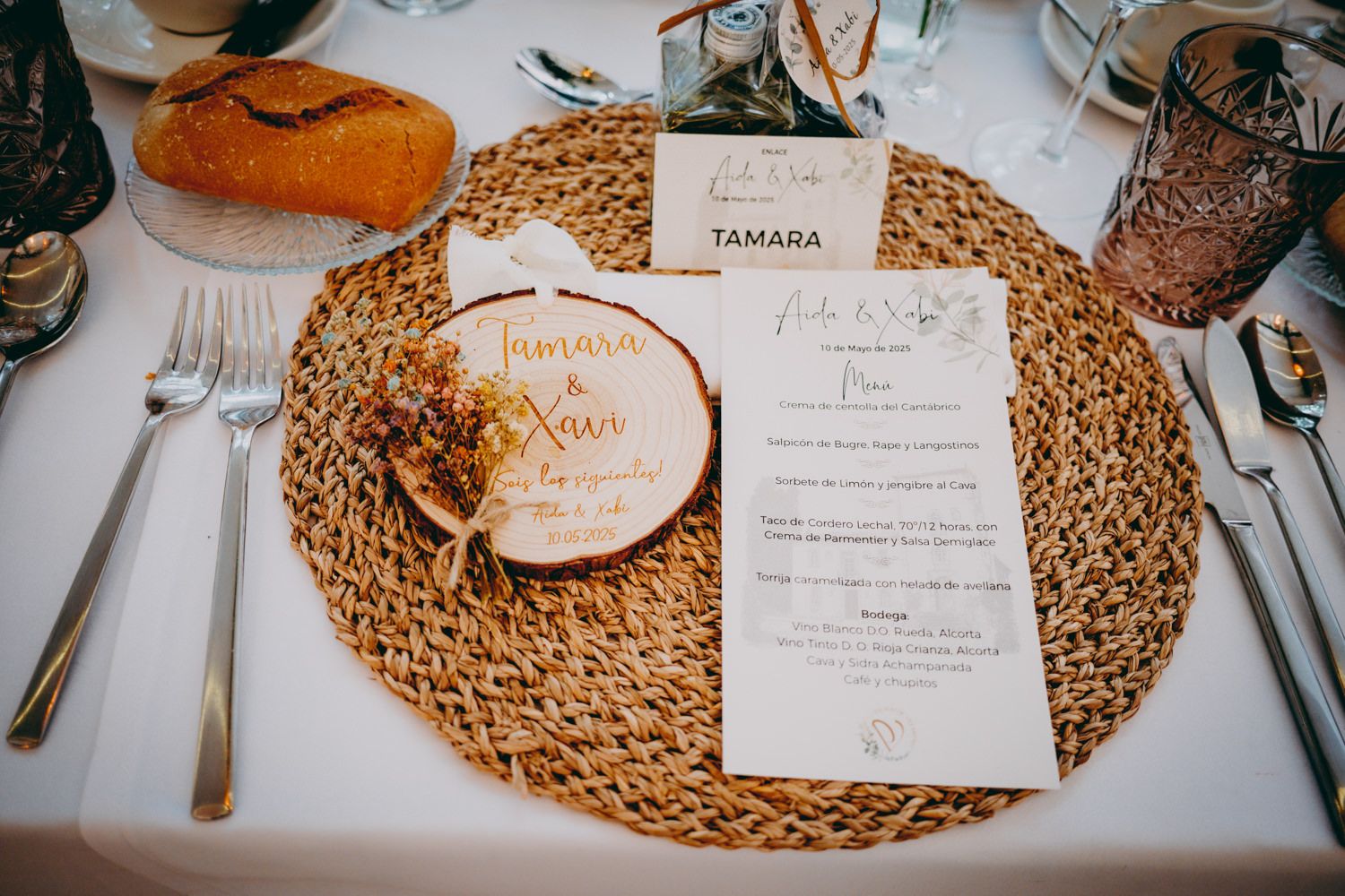 Decoración de mesa para boda con mantel tejido, tarjeta de menú y etiqueta con nombre sobre mantel blanco.