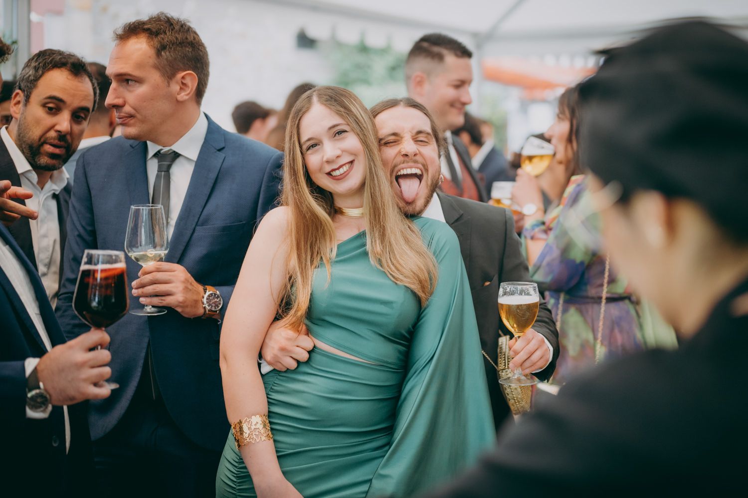 Invitados a la fiesta vestidos de manera formal disfrutando de bebidas y conversación en un evento elegante.