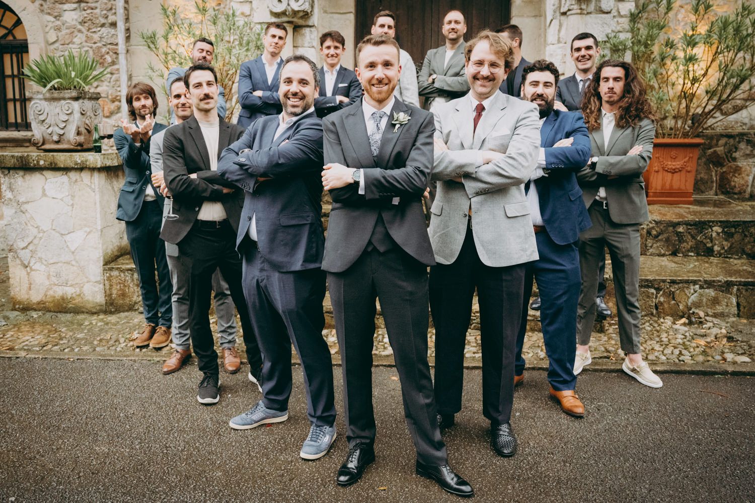 Padrinos de boda con traje posando dramáticamente juntos afuera del Palacio de Villabona.