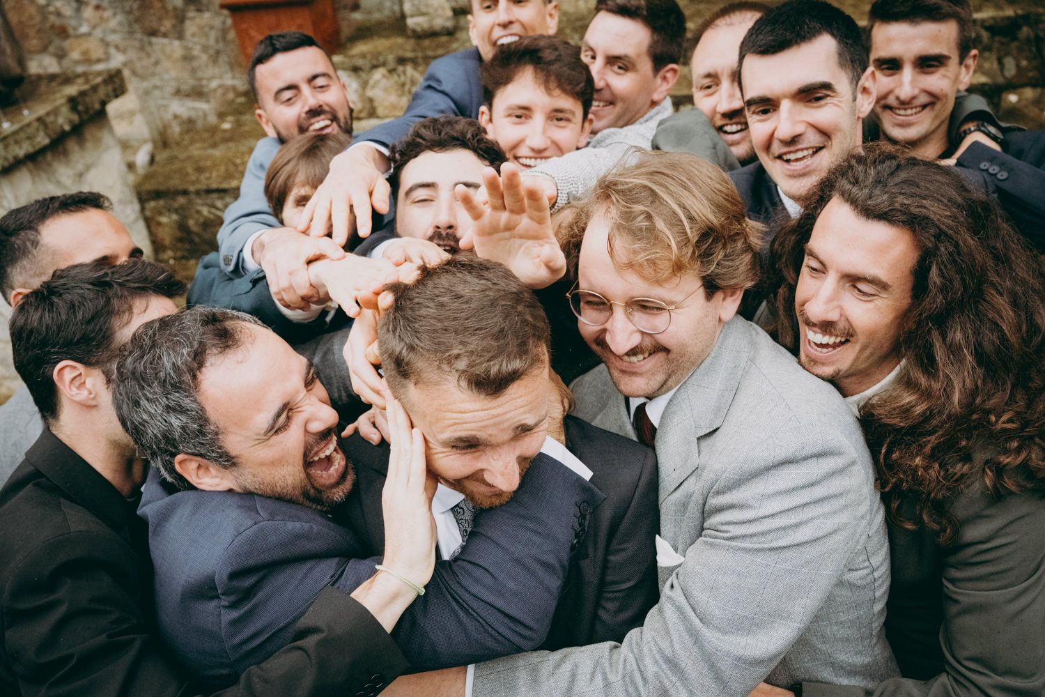 Grupo de amigos jugando bruscamente y riendo durante las celebraciones de la boda.