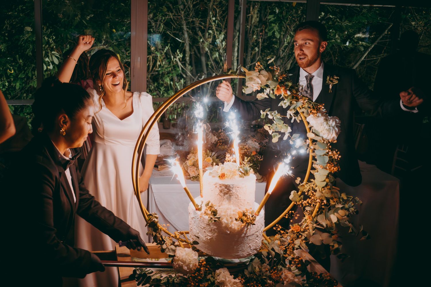 Celebración de bodas con un espejo con una corona floral iluminada decorativa que crea una atmósfera mágica de noche.