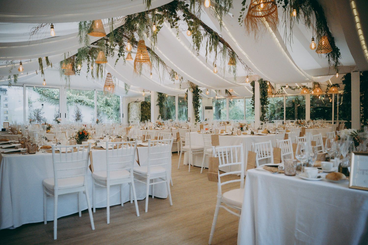 Elegante salón de recepción del Palacio de Villabona para bodas con sillas blancas, techo cubierto y vegetación colgante.