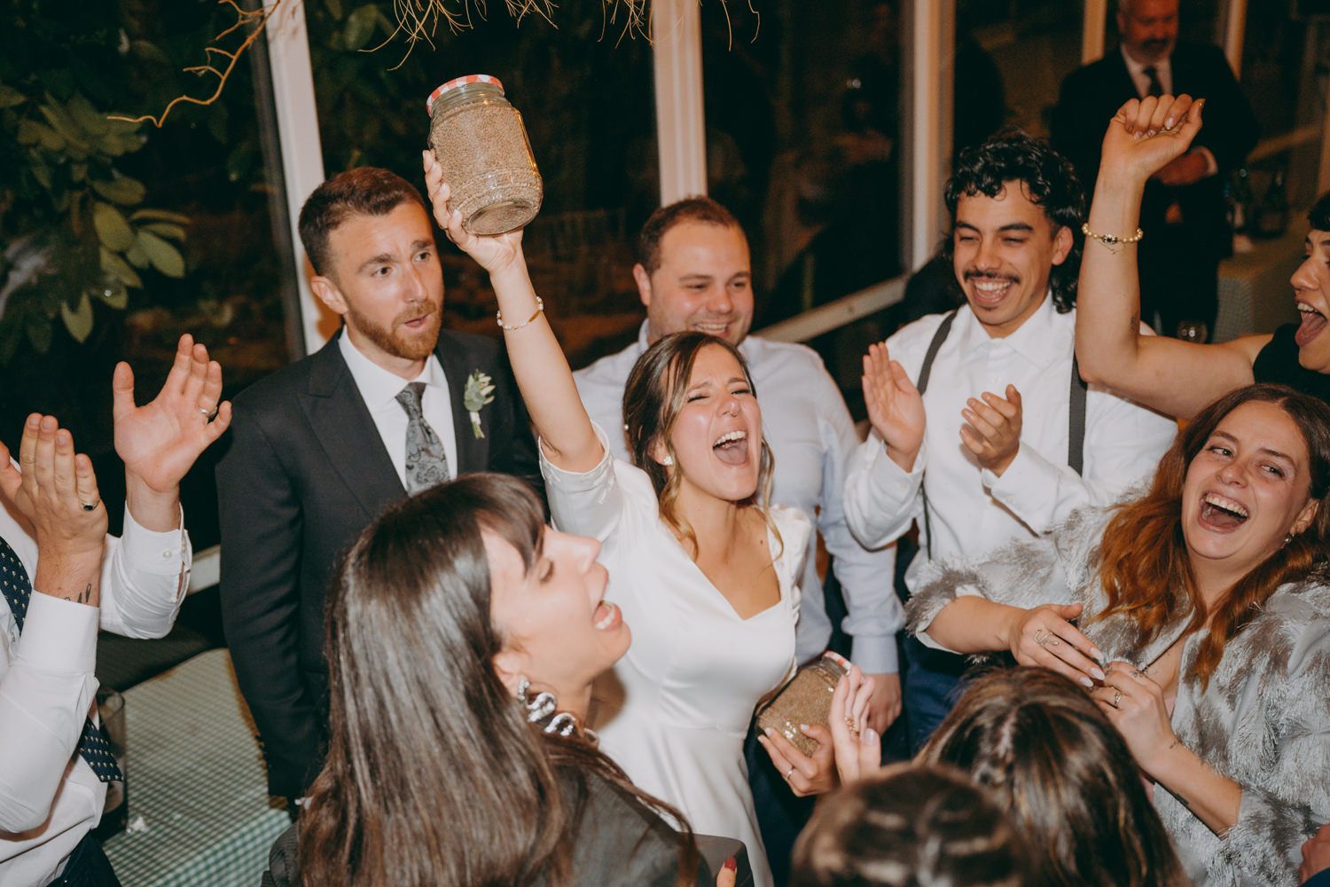 Los invitados a la boda celebran y bailan juntos con los brazos en alto durante una animada fiesta de recepción en el Palacio de Villabona