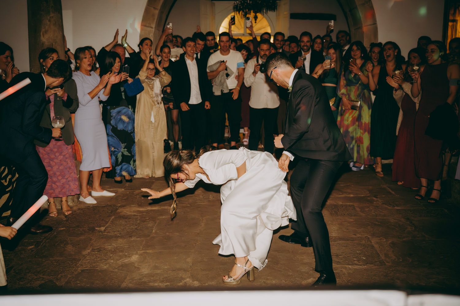 Los novios bailan en círculo mientras observan una dramática caída durante un baile sobre un piso de piedra en el Palacio de Villabona.
