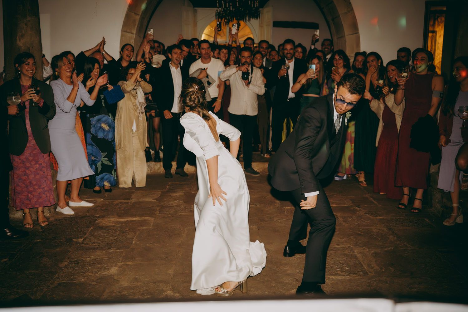 Una multitud de invitados a la boda forma un círculo alrededor de los novios en el interior del Palacio de Villabona.