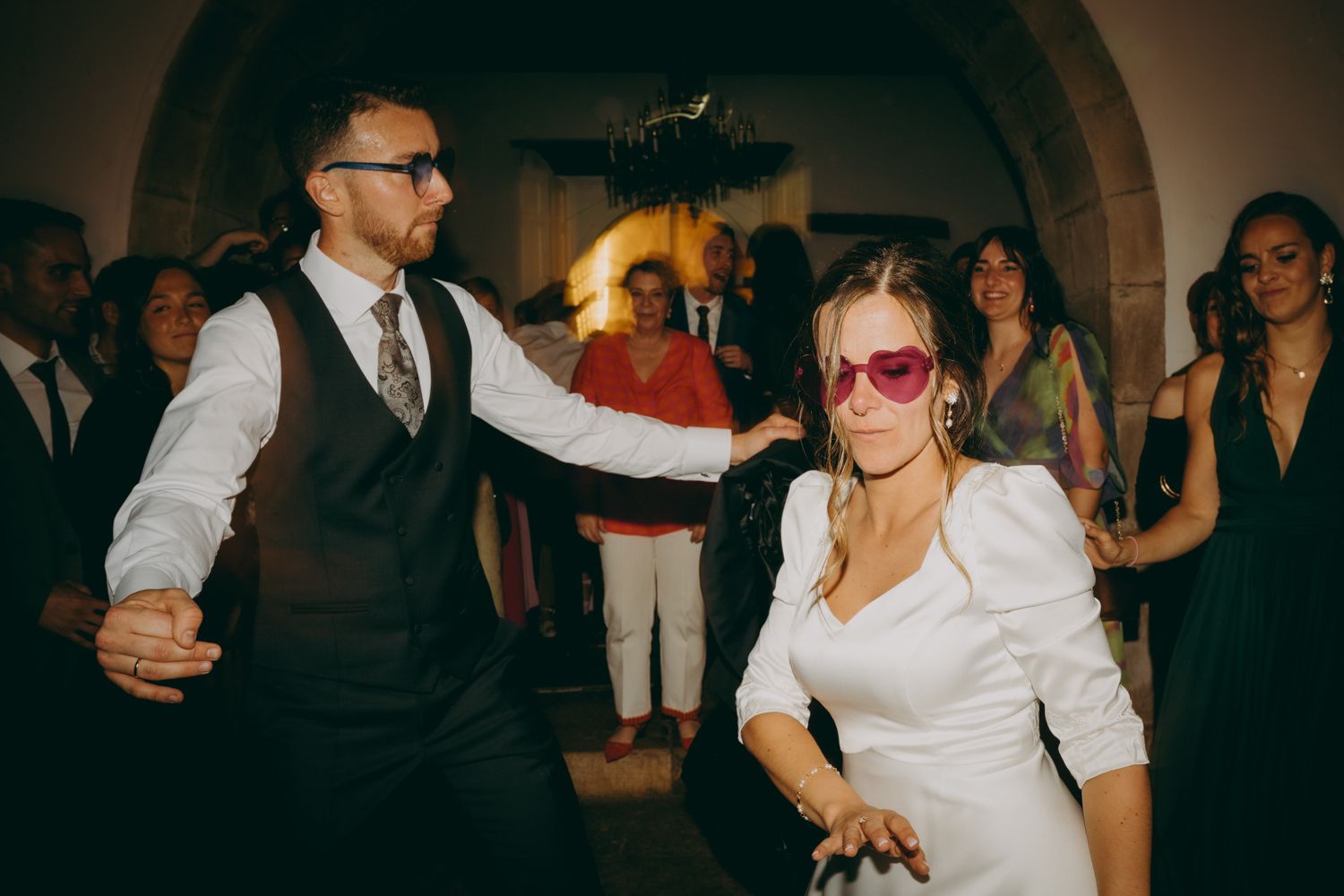 Novios bailan en una fiesta bajo puertas arqueadas con iluminación festiva en el Palacio de Villabona.