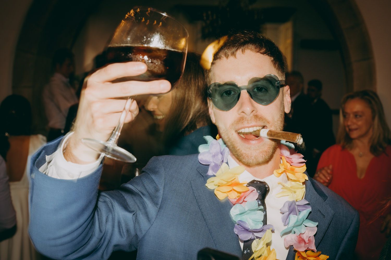 Un invitado que lleva gafas de sol sostiene una copa de vino en una boda del Palacio de Villabona.