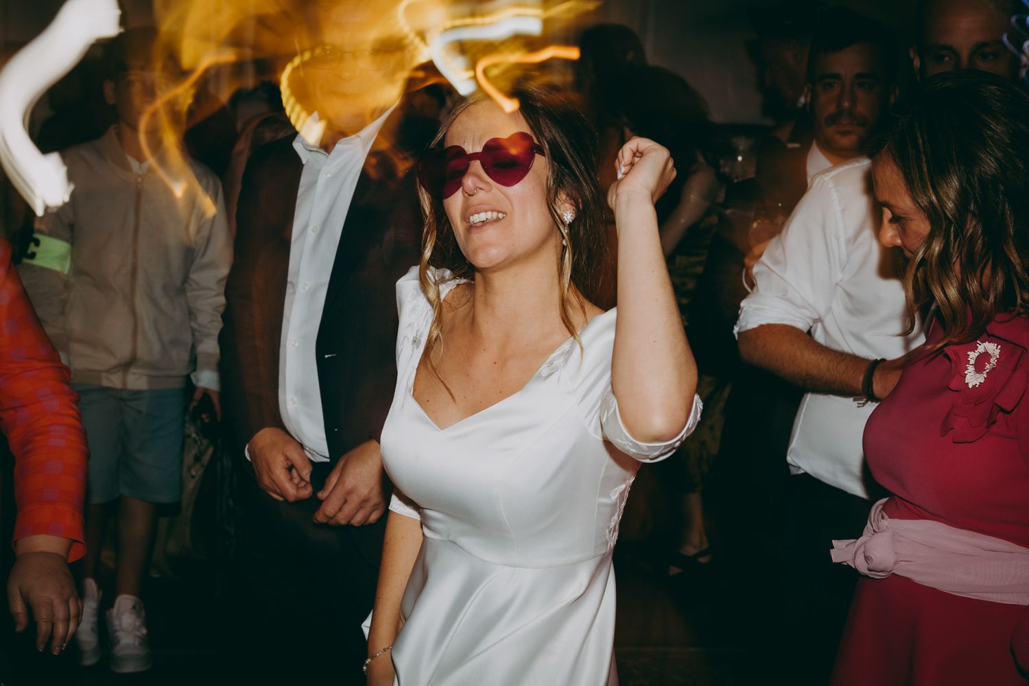 Novia con gafas de sol rojas bailando enérgicamente en una fiesta del Palacio de Villabona