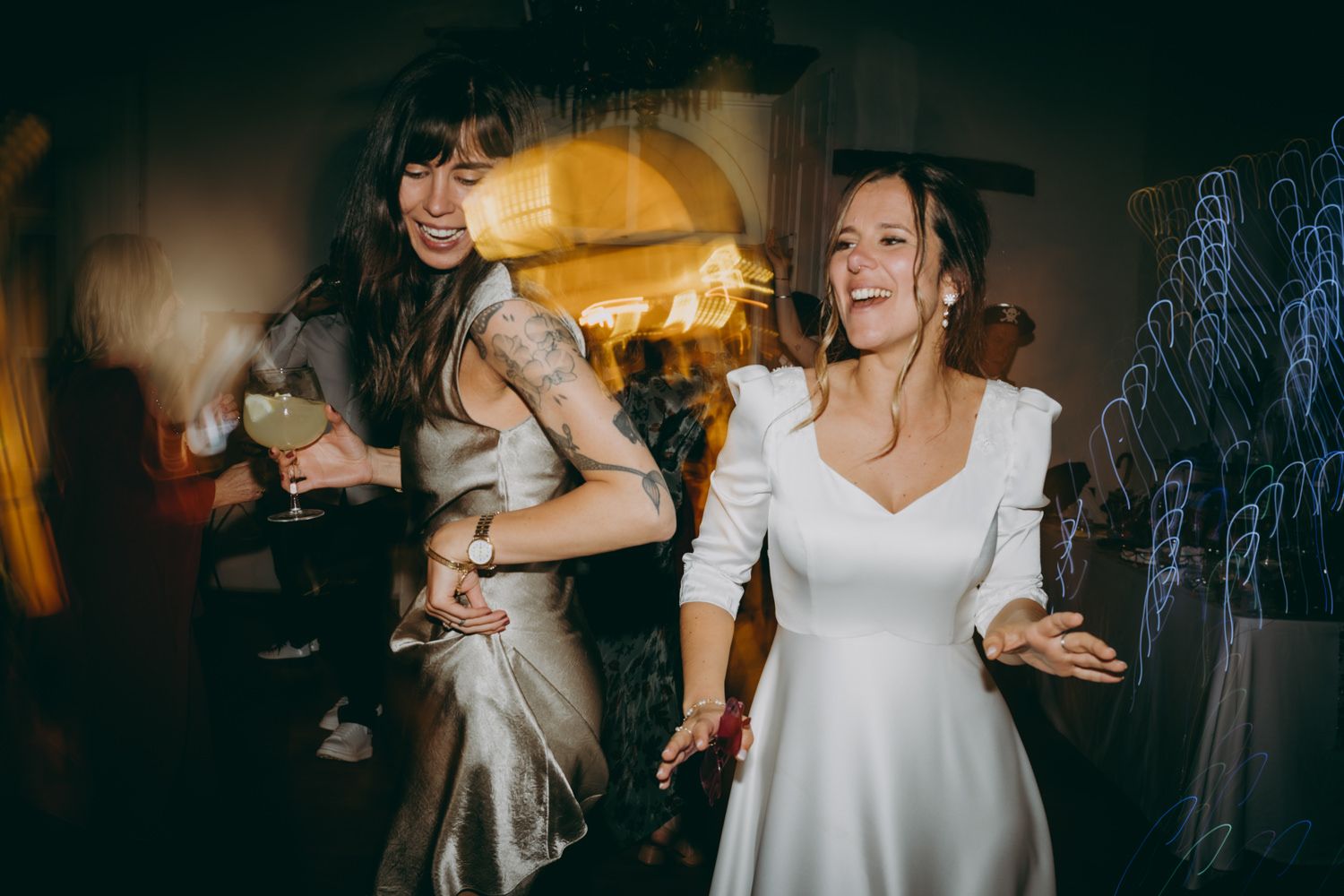 Invitada y novia bailan enérgicamente en la pista de baile con poca luz en el Palacio de Villabona.