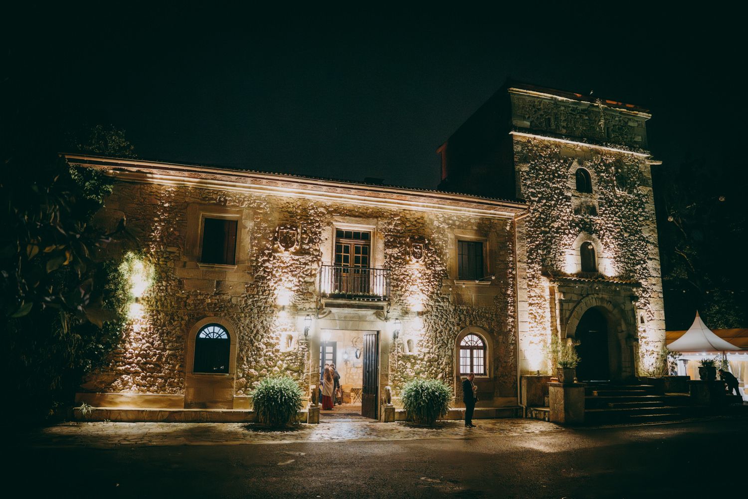 Palacio de Villabona iluminado por la noche con luz cálida y arco de entrada.