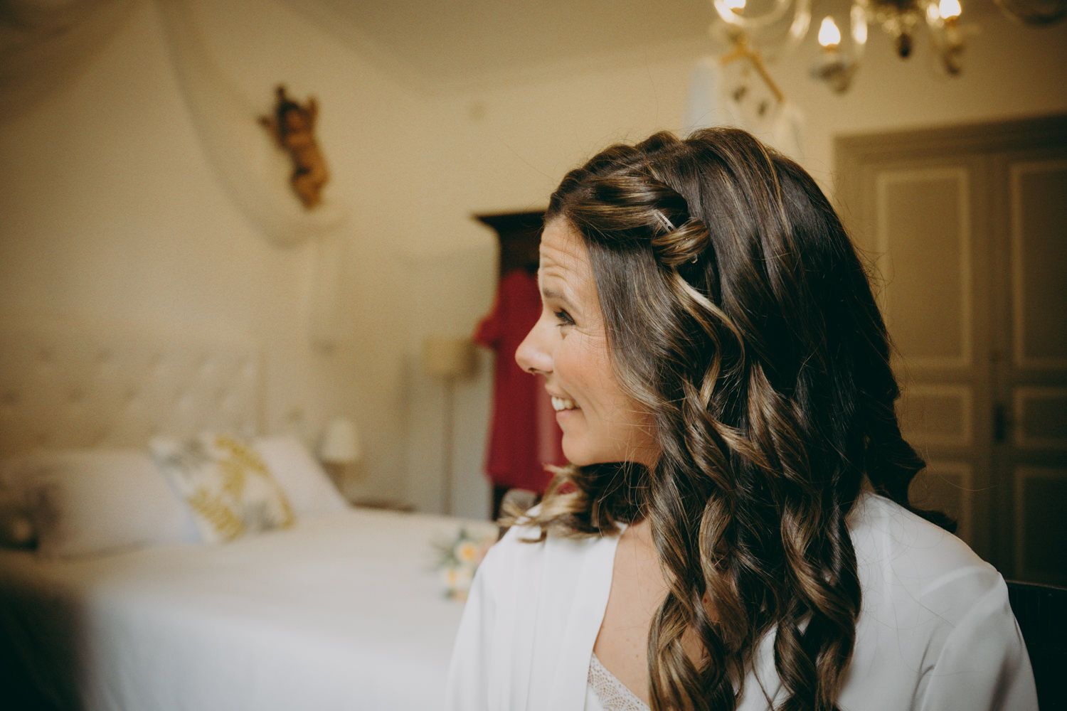 Perfil lateral que muestra cabello ondulado elegantemente peinado en un entorno de dormitorio.