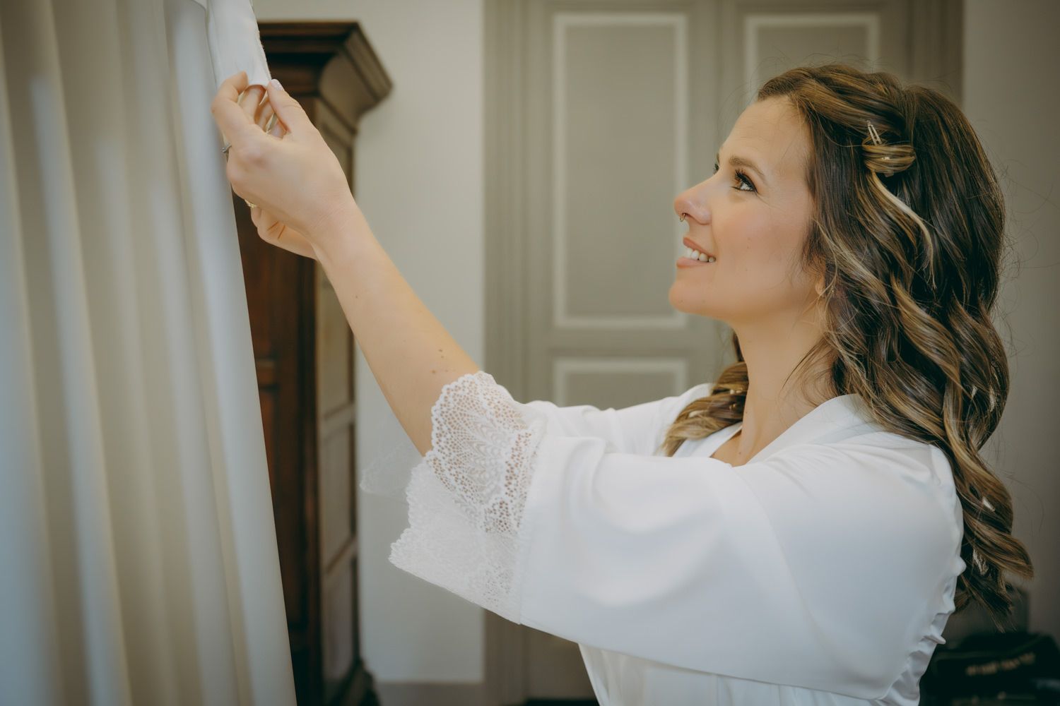 Una novia vestida de blanco se estira para ajustar algo mientras se prepara