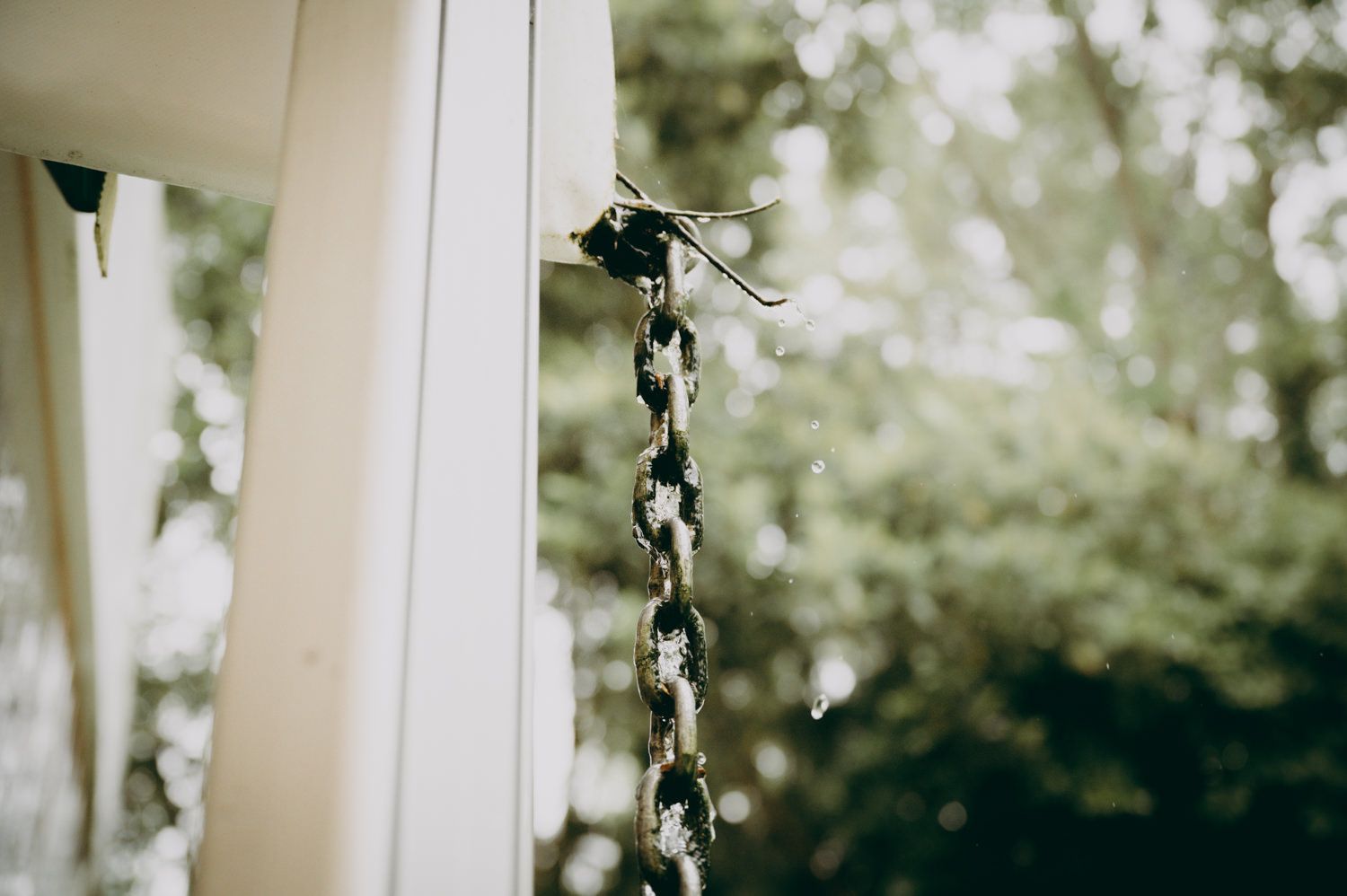 Una cadena decorativa de pequeñas luces blancas cuelga de un pilar blanco sobre un fondo exterior borroso.